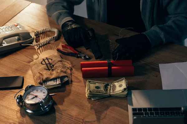 Vista parcial del terrorista con guantes negros con dinamita, armas y billetes de dólar - foto de stock