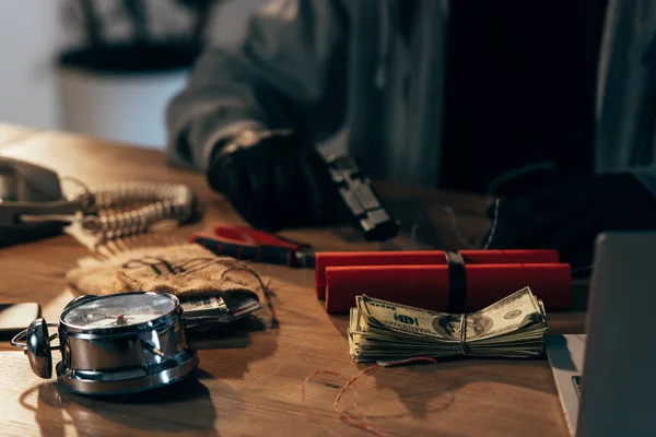 Partial view of terrorist sitting at table with money and weapon — Stock Photo