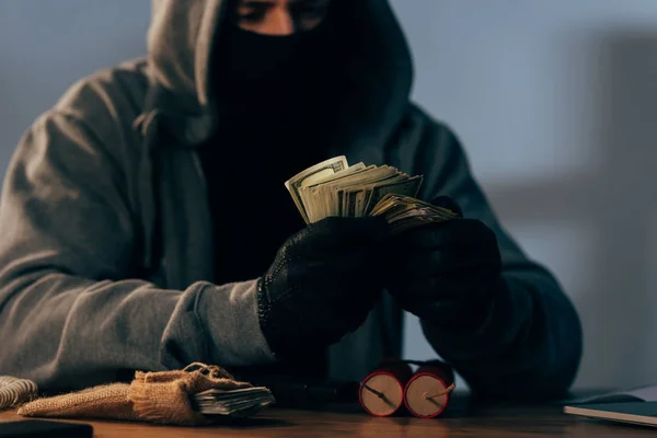 Vista parcial do terrorista mascarado contando notas de dólar — Fotografia de Stock