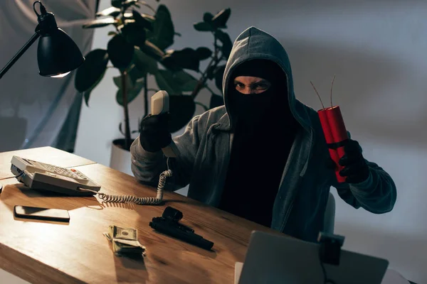 Terrorista enojado con máscara y guantes sosteniendo el auricular y la dinamita - foto de stock