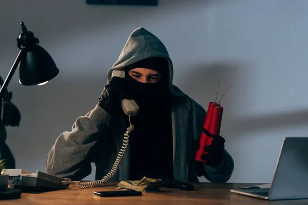 Террорист в маске держит динамит и разговаривает по телефону — стоковое фото