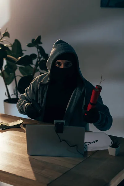 Terrorist with dynamite and laptop aiming gun at camera — Stock Photo