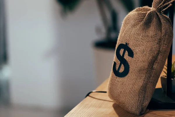 Money bag with dollar sign standing on wooden table — Stock Photo