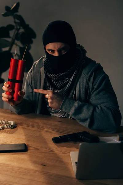 Terrorista enojado en máscara apuntando con el dedo a dinamita en la habitación - foto de stock