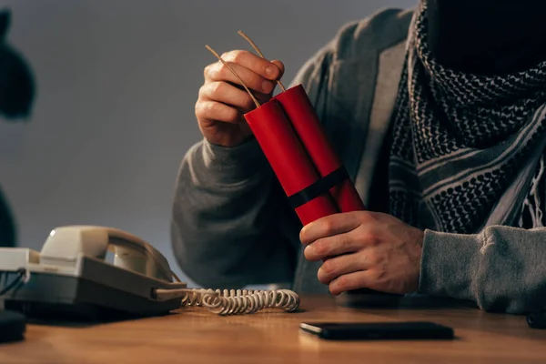 Cropped view of man holding dynamite at table in room — Stock Photo