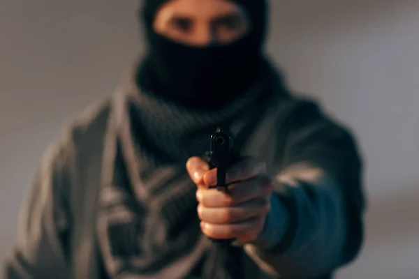 Terrorista en máscara y bufanda apuntando arma a cámara - foto de stock
