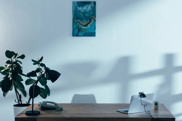 Ноутбук з веб-камерою, лампою і телефоном на столі в офісі — стокове фото