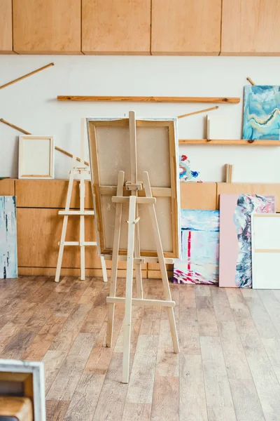 Spacious light painting studio with wooden cabinets, easels and paintings — Stock Photo