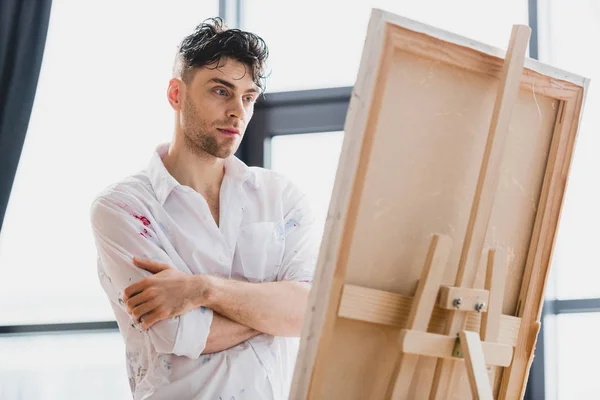 Gutaussehender, nachdenklicher Künstler im weißen Hemd mit Blick auf die Leinwand — Stockfoto