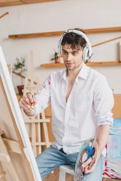 Enfoque selectivo de artista guapo escuchando música con auriculares - foto de stock