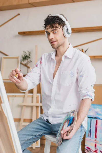 Enfoque selectivo de artista guapo escuchando música con auriculares - foto de stock