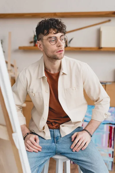 Selective focus of serious artist in eyeglasses looking away — Stock Photo