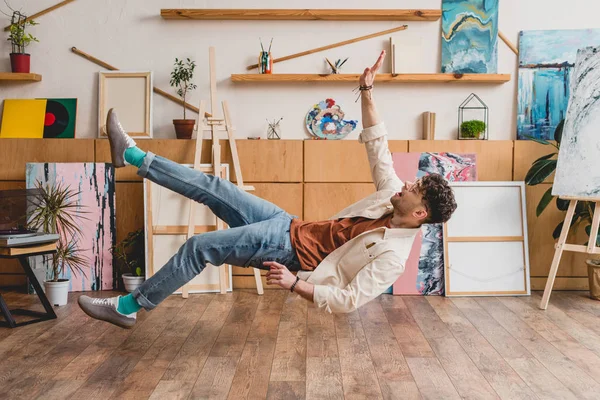 Beau artiste lévitant sur le sol en bois dans la galerie — Photo de stock