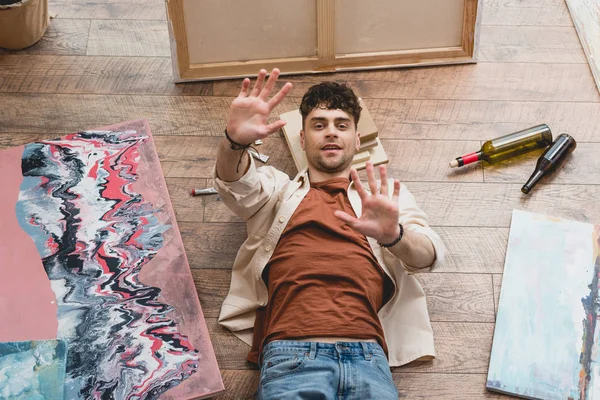 Художник зверху, що лежить на дерев'яній підлозі з розтягнутими руками — стокове фото