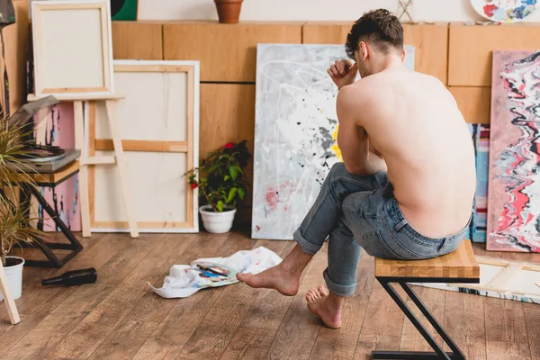 Exhausted half-naked artist sitting on chair in painting studio — Stock Photo