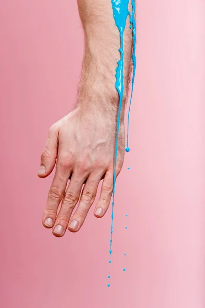 Parcial com de homem com derramamentos de tinta azul na mão em rosa — Fotografia de Stock