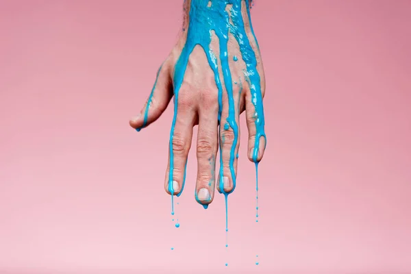 Recortado con de mano masculina con derrames de pintura azul sobre rosa - foto de stock