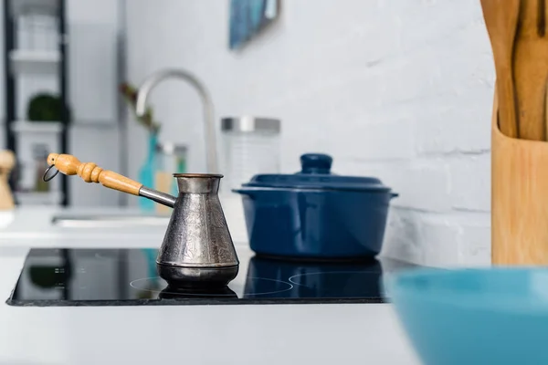 Selective focus of turkish metal cezve with handle on oven in kitchen — Stock Photo