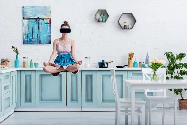 Mujer joven levitando en el aire en pose de loto y en auriculares de realidad virtual - foto de stock