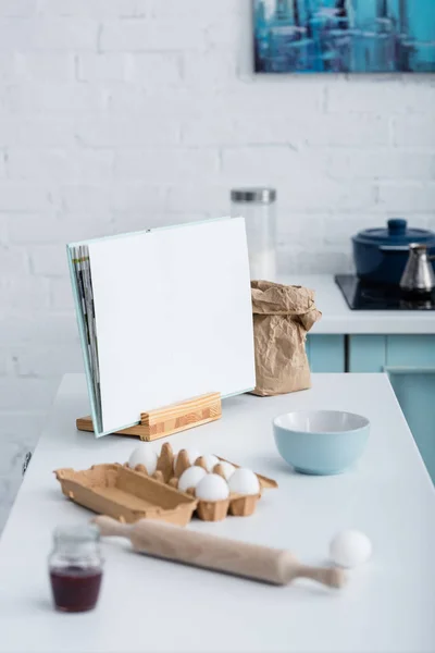 Livro de receitas aberto vazio na mesa com utensílios de cozinha e ingredientes de padaria — Fotografia de Stock