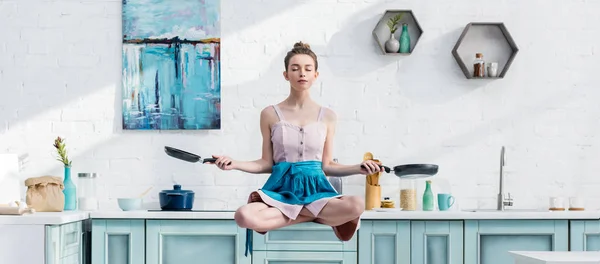 Panoramic shot of young woman meditating in air with pans — Stock Photo