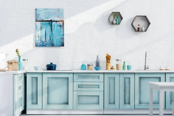 Interior de cocina elegante turquesa y blanca con utensilios de cocina, decoración y luz solar — Stock Photo