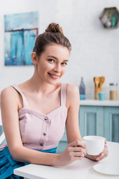 Glücklich schöne junge Frau sitzt am Tisch und trinkt Kaffee — Stockfoto