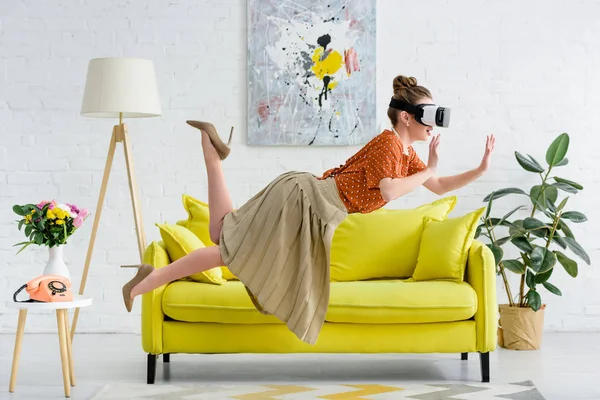 Vista lateral da jovem mulher elegante levitando no ar enquanto vestindo fone de ouvido realidade virtual — Fotografia de Stock