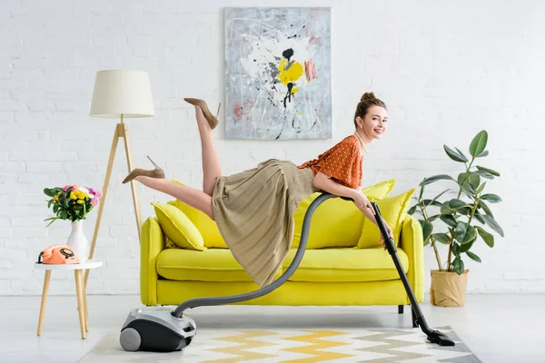 Elegant smiling young woman levitating in air and holding vacuum cleaner — Stock Photo