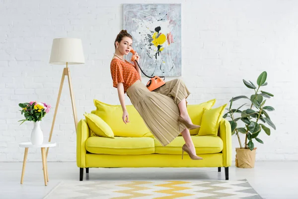 Elegant young woman levitating in air and talking on vintage phone in living room — Stock Photo