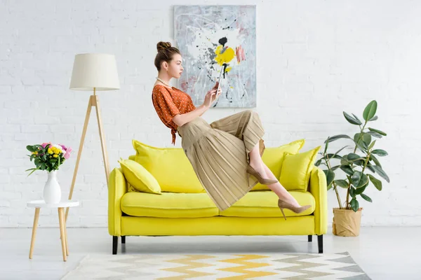 Elegant young woman levitating in air and using digital tablet in living room — Stock Photo