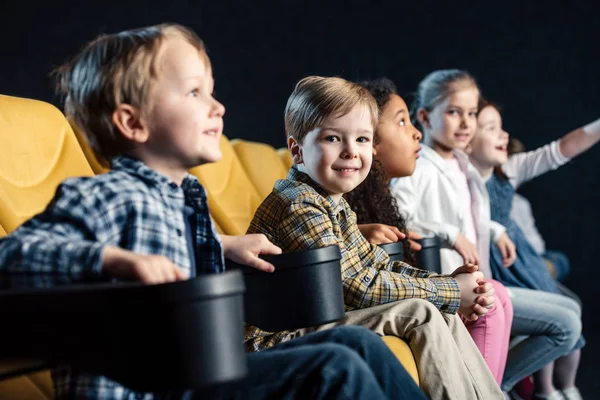 Fuoco selettivo di sorridere allegri amici multiculturali guardando film nel cinema insieme — Foto stock