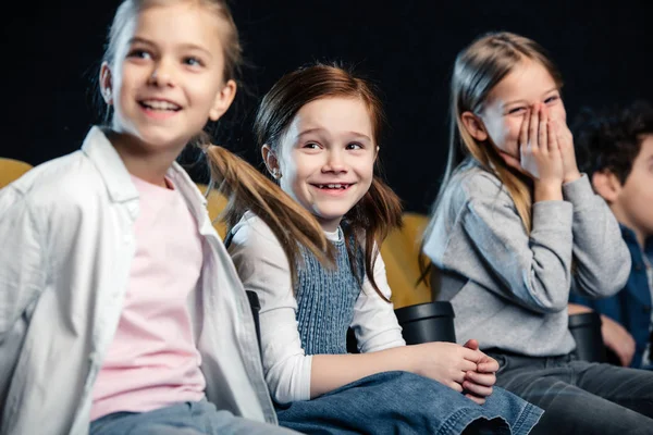 Amigos alegres sentados en el cine y viendo películas con amigos multiculturales - foto de stock