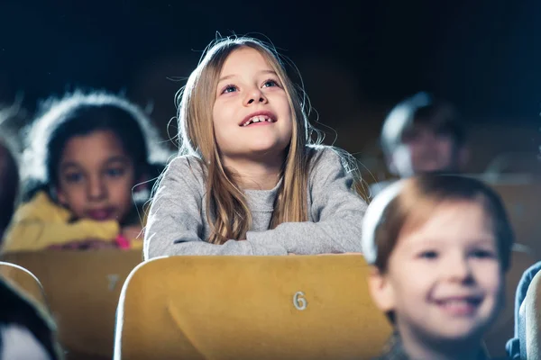 Вибірковий фокус мила усміхнена дитина дивиться фільм разом з мультикультурними друзями — стокове фото