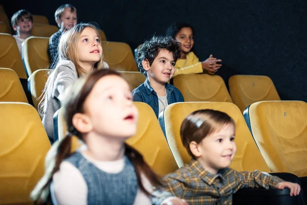 Selective focus of multicultural friends watching movie in cinema — Stock Photo