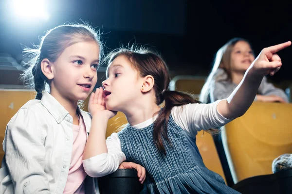 Nettes Kind zeigt mit dem Finger und spricht mit Freund im Kino — Stockfoto