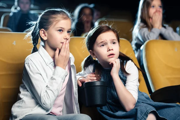 Crianças preocupadas assistindo filme no cinema junto com amigos multiculturais — Fotografia de Stock