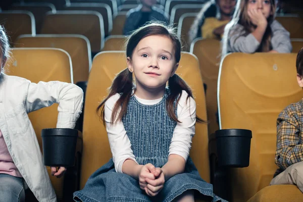 Adorabile bambino guardando film in cinema insieme con amici multiculturali — Foto stock