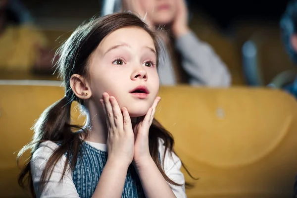 Selective focus of cute worried child watching movie in cinema — Stock Photo