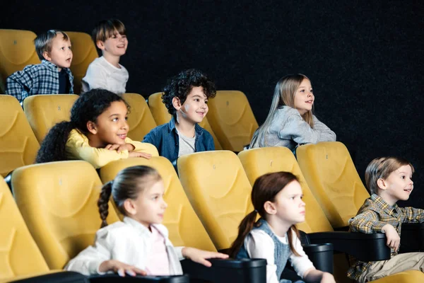 Amici multiculturali sorridenti che guardano film nel cinema insieme — Foto stock