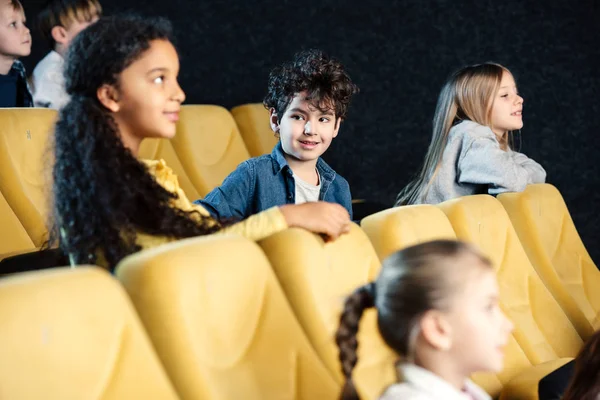 Foyer sélectif des enfants multiculturels assis dans le cinéma et regarder des films — Photo de stock
