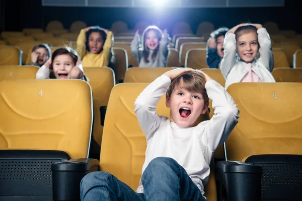 Excité amis multiculturels regarder un film dans le cinéma ensemble — Photo de stock