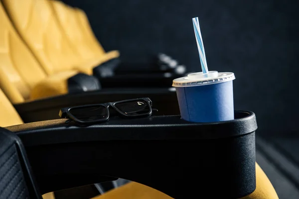 Mise au point sélective de sièges cinéma orange vides avec gobelet d'élimination et verres 3D — Photo de stock