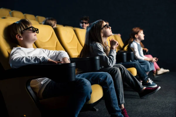 Amis attentifs dans des lunettes 3D assis dans des sièges confortables et regarder des films au cinéma — Photo de stock