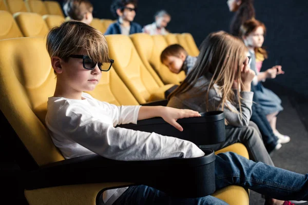 Amigos multiculturales en gafas 3D sentados en cómodos asientos en el cine - foto de stock