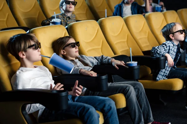 Друзі в 3d окулярах дивитися фільм в кіно і тримають паперові чашки — стокове фото