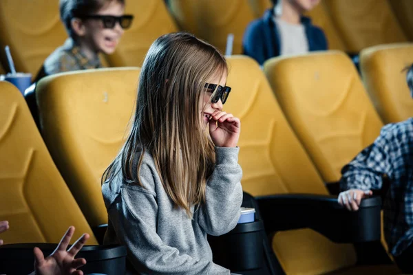 Selektiver Fokus eines lächelnden Kindes in 3D-Brille, das im Kino sitzt und sich einen Film ansieht — Stockfoto