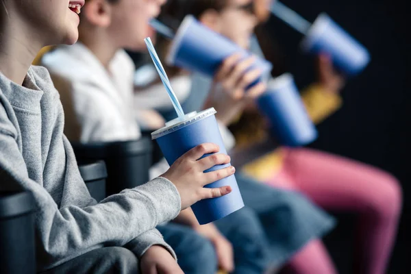 Enfoque selectivo de amigos viendo películas en el cine y sosteniendo vasos de papel - foto de stock