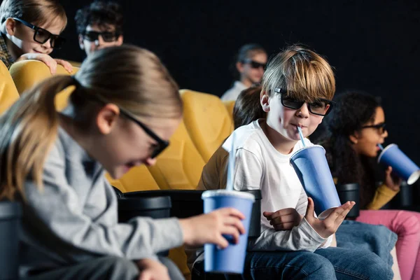 Enfoque selectivo de amigos multiculturales sonrientes en gafas 3D sosteniendo vasos de papel - foto de stock