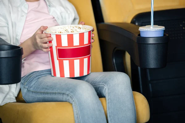 Cropped view of child holding stripped paper cup with popcorn — Stock Photo